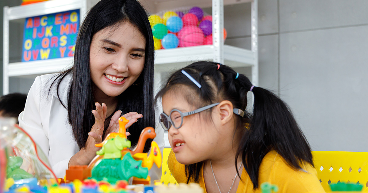 Woman in role of Disability Support Work playing toys with young girl